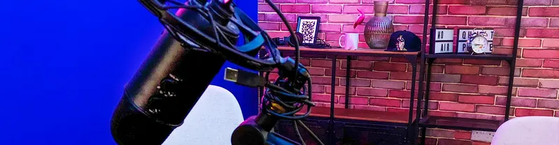 Stúdiómikrofon kék háttér előtt, mögötte téglafalas, neonfényes podcast díszlet